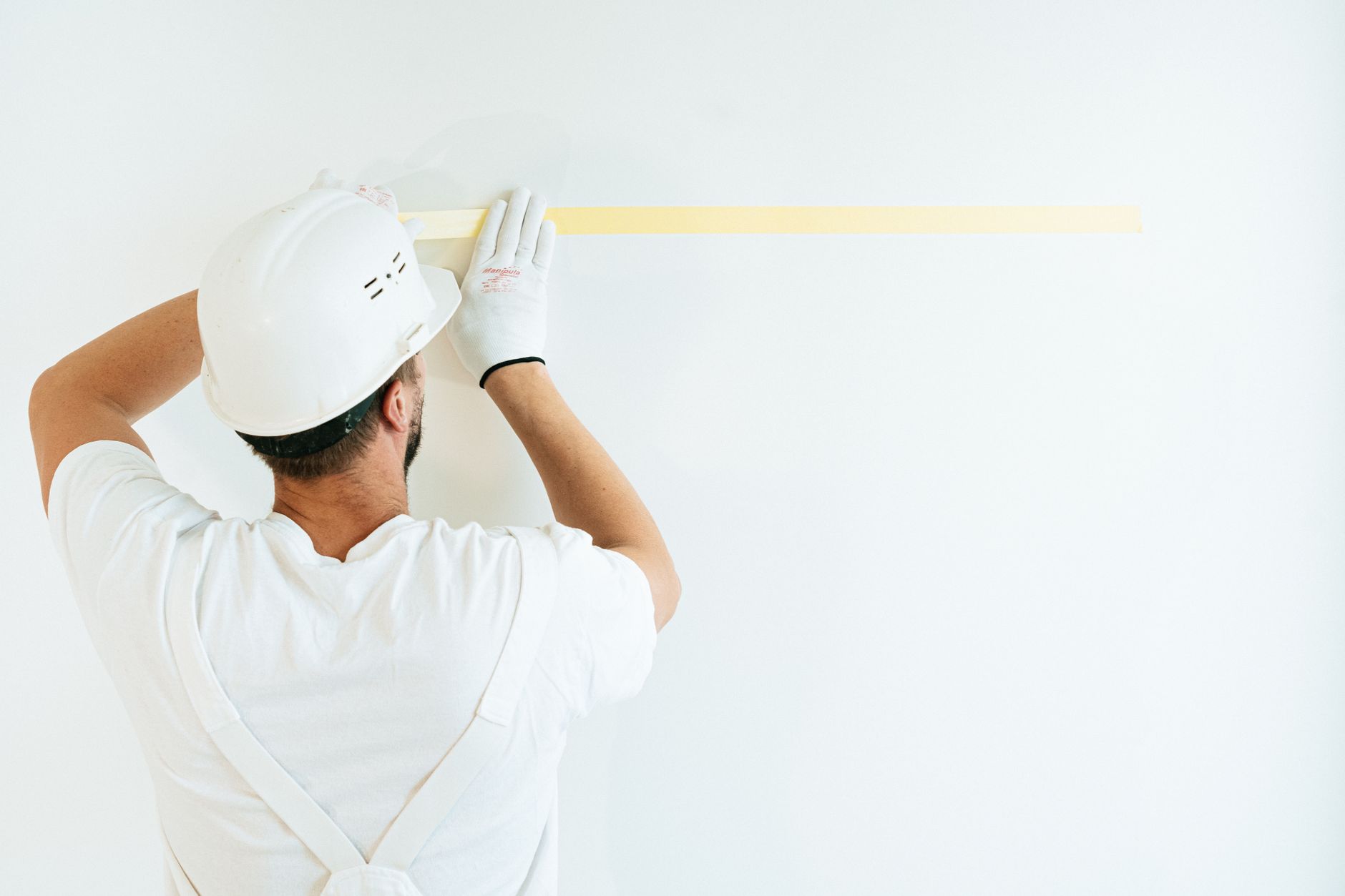 Schilder plakt een wand nauwkeurig af met schilderstape